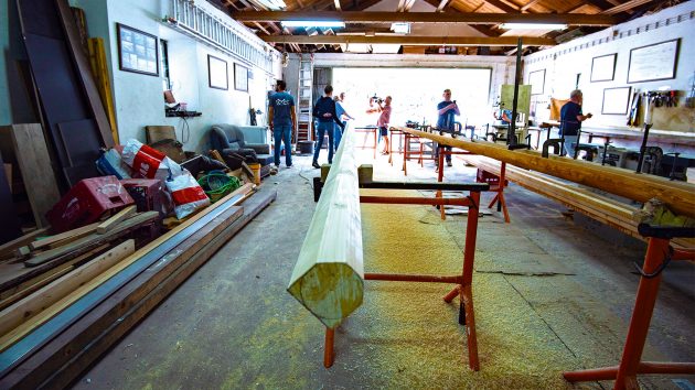 A stripped tree trunk lying on some supports in a workshop.