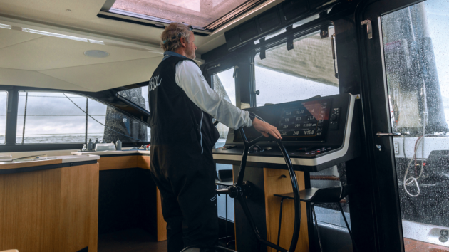 Person standing inside a yacht looking out a window.